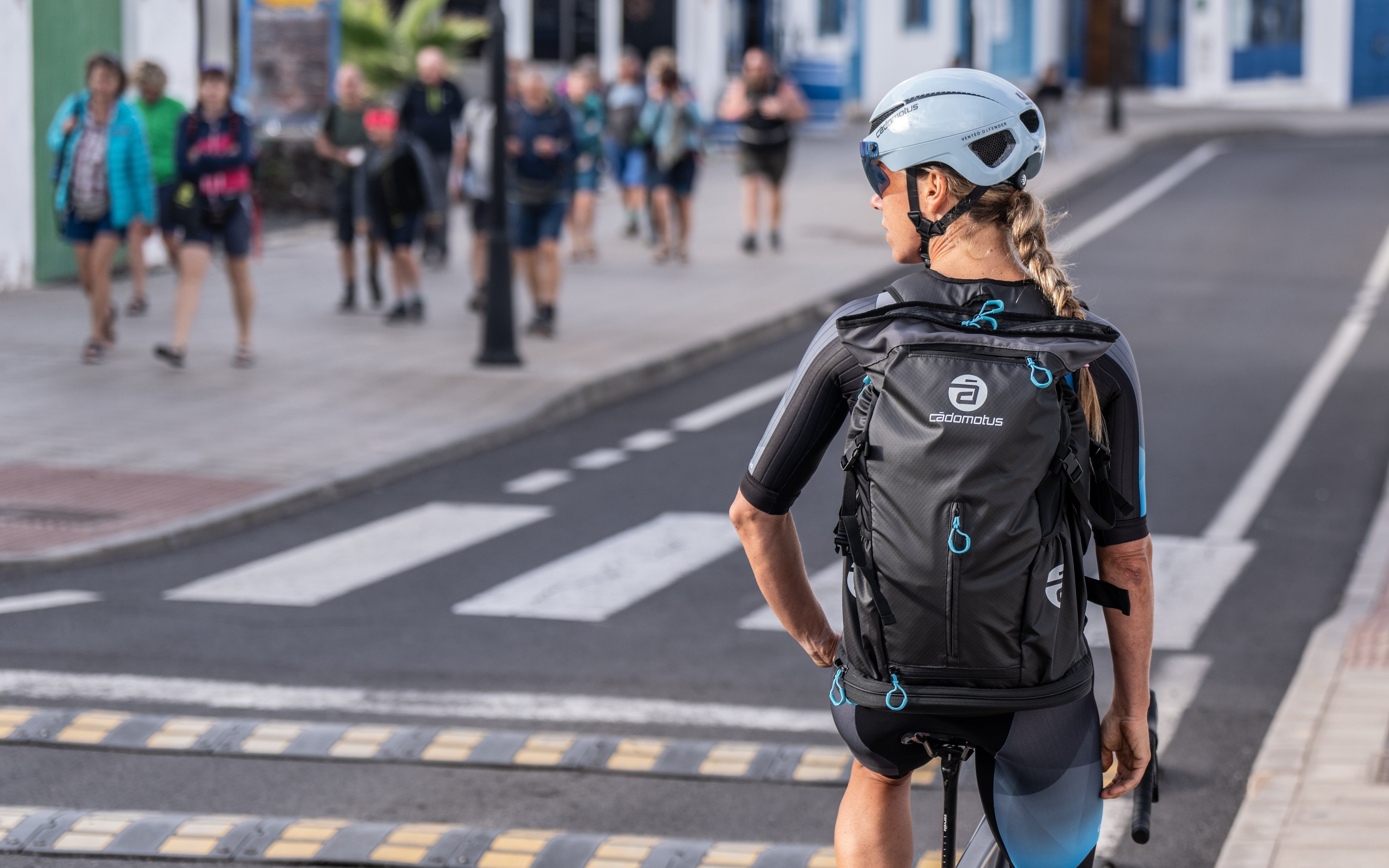 Eine Radfahrerin steht an einer Straßenkreuzung mit einem Cadomotus Rucksack auf dem Rücken 