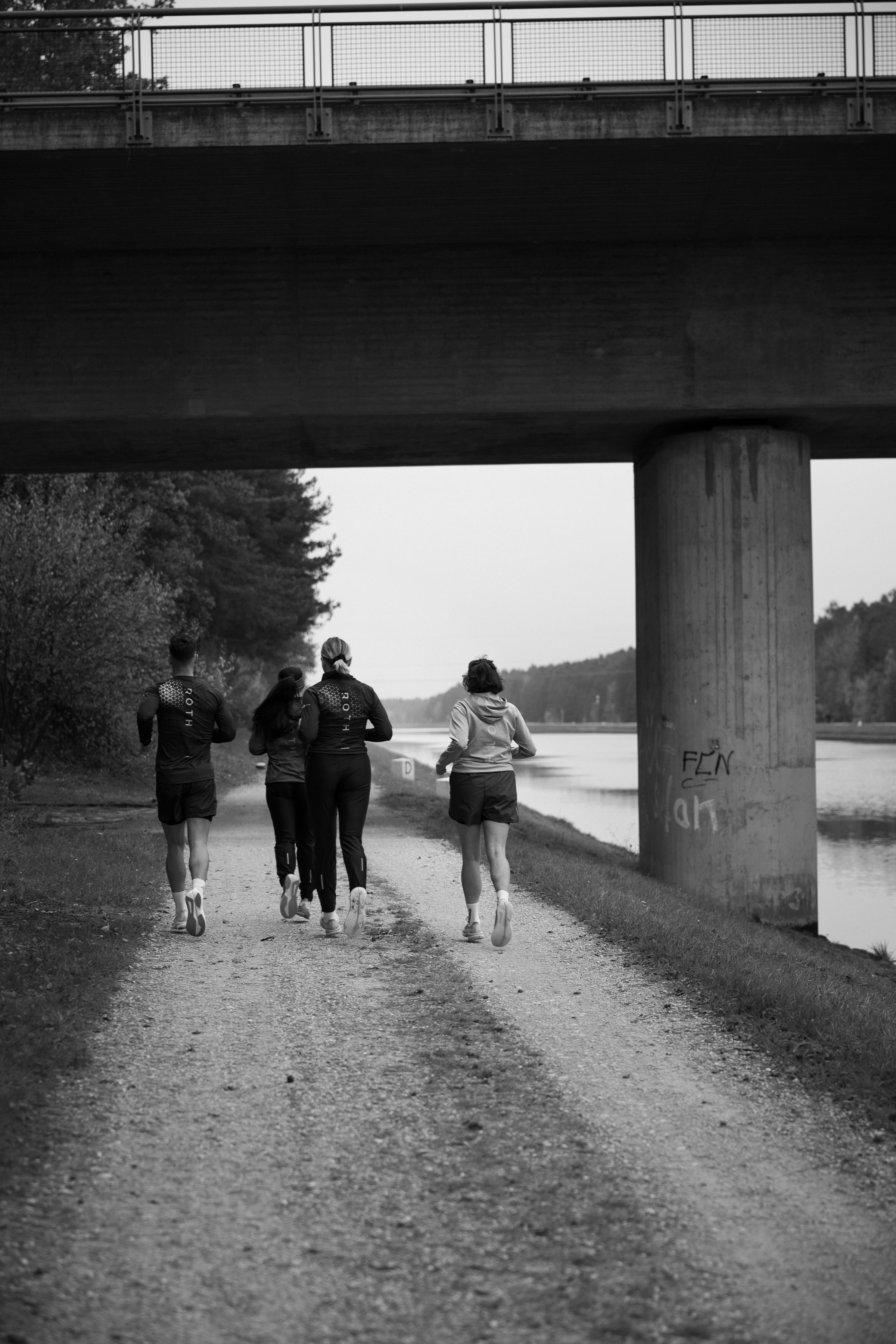 4 Menschen in der Laufkollektion von ROTH laufen zusammen am Kanal